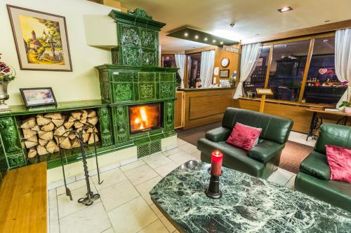 a living room with a fireplace and green furniture at Hotel Sachticka in Banská Bystrica