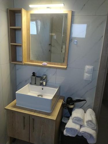 a bathroom with a sink and a mirror and towels at Dimis Apartment in Chrysoupolis