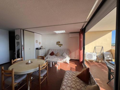 un salon avec une table et un canapé dans l'établissement Appartement T2 Climatisé avec Piscine, Terrasse et Accès Direct Plage, 4 Couchages – Le Barcarès - FR-1-81-510, au Barcarès
