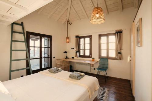 ein Schlafzimmer mit einem Bett, einem Schreibtisch und Fenstern in der Unterkunft Great Pelion Villa Villa Iris 4 Bedrooms Private Pool in Pilion