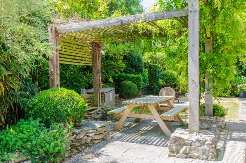 a picnic table and a wooden pergola in a garden at Luxury Victorian school with views of Harbour in Fowey