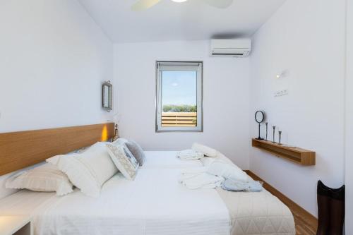a white bedroom with a bed and a window at Extraordinary Rethymno Villa Villa Hantengu 3 Bedrooms Beach Front Private Outdoor Swimming Pool And Hot Tub Pigianos Kampos in Pigianos Kampos