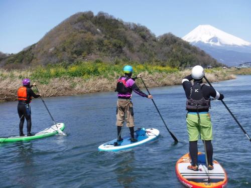 three people are standing on paddle boards on a river at COCOTIER Enjoy a Free and Easy BBQ at a Cool Villa in Izu Best of Vacation Rentals 4 in Izunokuni