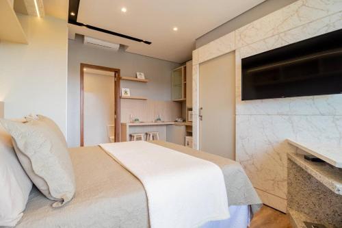 a bedroom with a bed and a tv on the wall at Pousada Natribus Rosa in Praia do Rosa