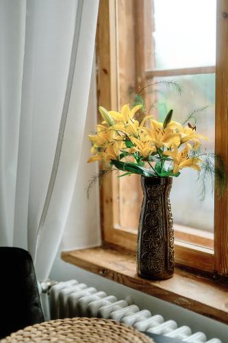 a vase with yellow flowers sitting on a window sill at Your Lutsu Apartment Lux Retro Prime Spot in Viljandi