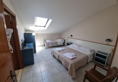 a hotel room with two beds and a chair at Hotel Anny in Cervia