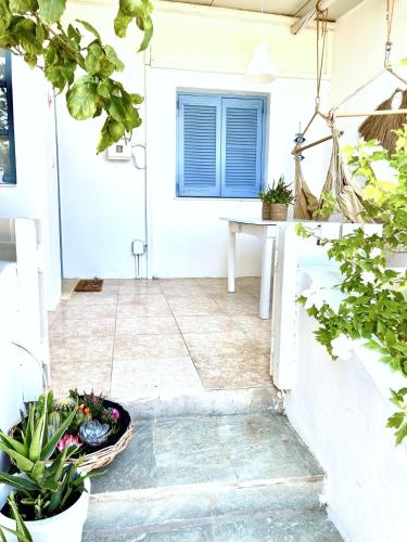 a porch with potted plants in front of a white door at Lemon Tree House, Golden Beach in Chrissi Akti