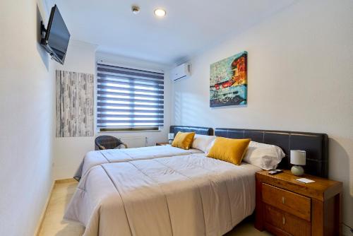 a bedroom with a bed with yellow pillows and a television at Hotel Villamayor by gaiarooms in Villamayor