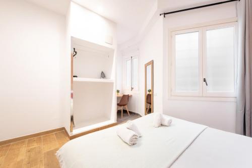 a white bedroom with a white bed and a mirror at Caliu Apartments Barcelona - Fira in Hospitalet de Llobregat