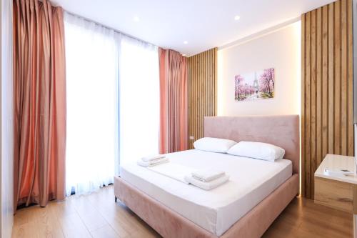 a bedroom with a white bed and a large window at SanPietro Vacation Apartments in Durrës