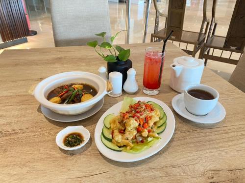 a table with a plate of food and a bowl of soup at Alltrue Sydney Hotel Batam Center in Batam Center