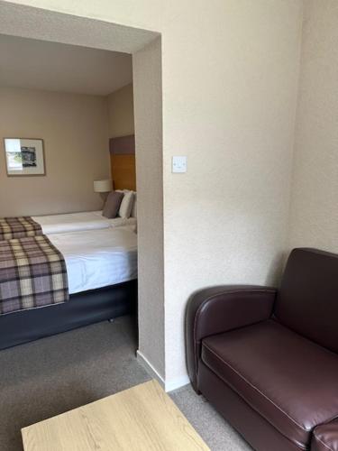 a room with a bed and a couch and a chair at The Acarsaid - Pitlochry in Pitlochry