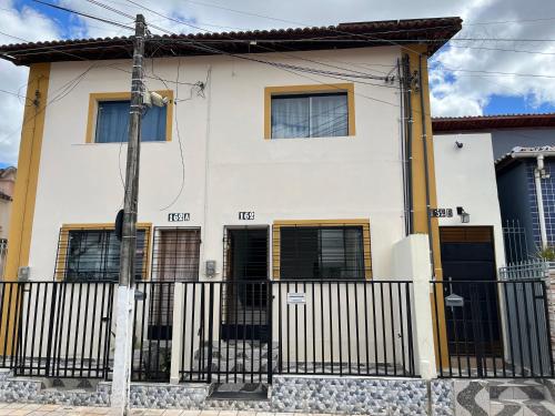 une maison blanche avec des portes noires et une clôture dans l'établissement Apto ao lado da Praça da Sé, ótima localização, à Crato