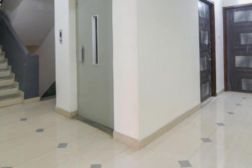 a hallway with a white wall and a staircase at Hotel O GEMS STAR RESIDENCY BNB Bamandongri Railway Station in Belapurpāda