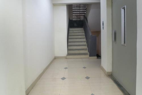 a hallway with a staircase and a tile floor at Hotel O GEMS STAR RESIDENCY BNB Bamandongri Railway Station in Belapurpāda