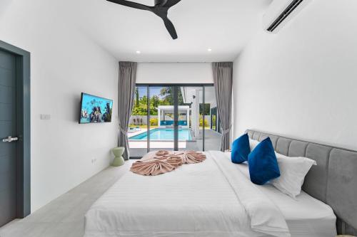 Un dormitorio con una gran cama blanca con almohadas azules. en MANEE Jasmine Pool Villa, Bangrak, Bo Phut, Fisherman's Village, en Bangrak Beach