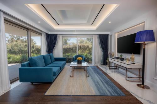 a living room with a blue couch and a table at Merit Royal Gardens Hotel & Casino in İskele