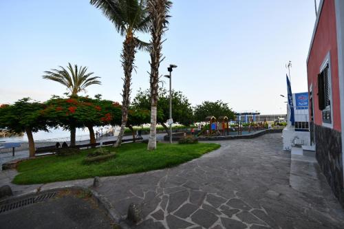 a park with palm trees and a playground next to the water at Sandy Shores Oasis in Playa de San Juan