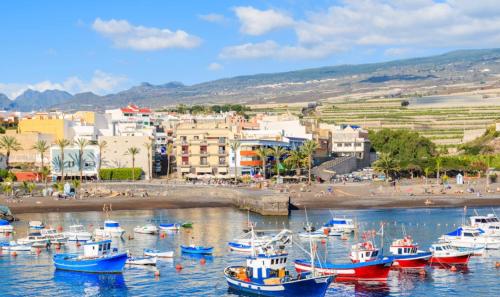 a group of boats in the water near a city at Sandy Shores Oasis in Playa de San Juan