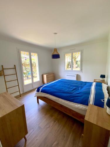 a bedroom with a bed with a blue comforter and two windows at Villa Labenne Ocean - piscine, 500 mètres de la plage in Labenne