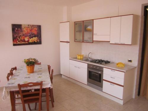 a kitchen with white cabinets and a table with a dining room at La Veranda in Margherita di Savoia