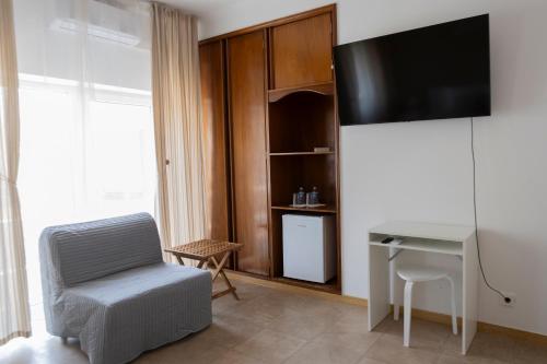 a room with a desk and a tv and a chair at Residencial Princesa do Ave in Vila do Conde