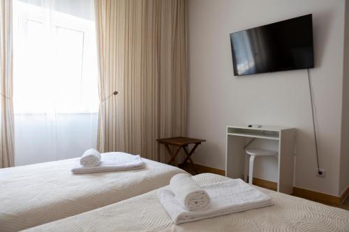 a hotel room with a bed and a flat screen tv at Residencial Princesa do Ave in Vila do Conde