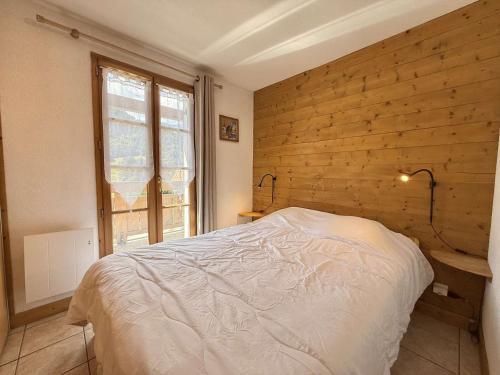 une chambre avec un lit et un mur en bois dans l'établissement Appartement cosy à Flumet, 3 chambres, balcon sud, Wi-Fi, parking, près des pistes et navettes gratuites - FR-1-595-61, à Flumet