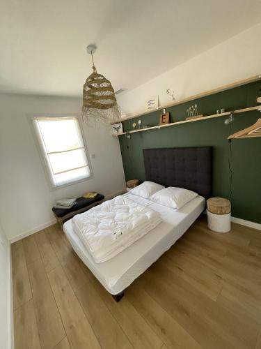 une chambre avec un grand lit blanc et une fenêtre dans l'établissement Casa Côme, à Saint-Vincent-sur-Jard