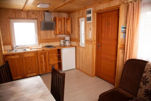 a kitchen with wooden cabinets and a white refrigerator at Domki Letniskowe Bursztynek in Grzybowo