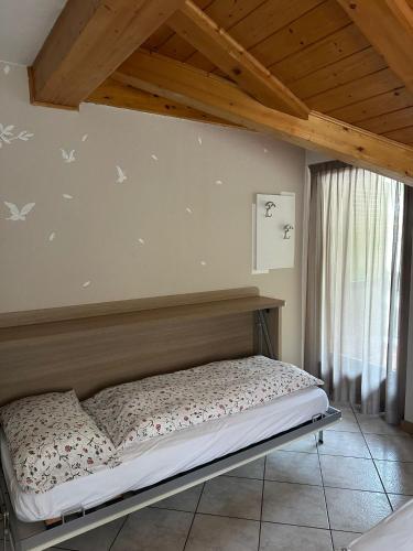 a bed in a room with a wooden ceiling at Villa Giardino - Flowers in Molveno