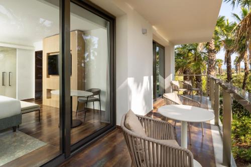 una camera con balcone arredato con tavoli e sedie. di Algarve Marriott Salgados Golf Resort & Spa ad Albufeira