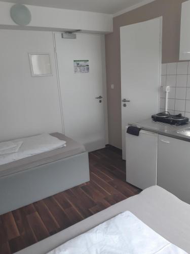 a kitchen with white cabinets and a wooden floor at 2-Rent Group Hostel Apartments SEN14 in Munich
