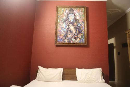 a painting on the wall above a bed in a room at Vedic Dham Ganga in Rishīkesh
