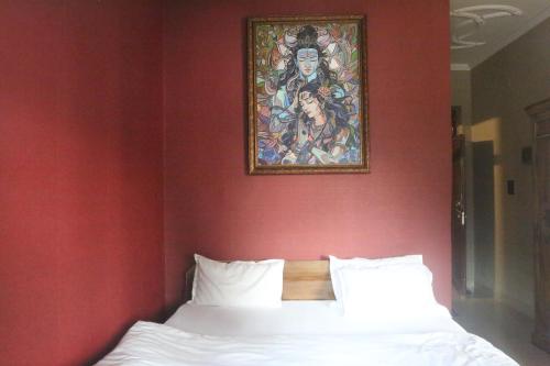a bed in a red room with a painting on the wall at Vedic Dham Ganga in Rishīkesh