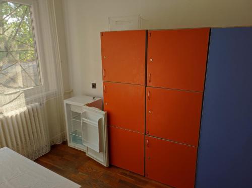 an orange cabinet in a room with a window at Alexander Munkásszálló Oroszlány in Oroszlány