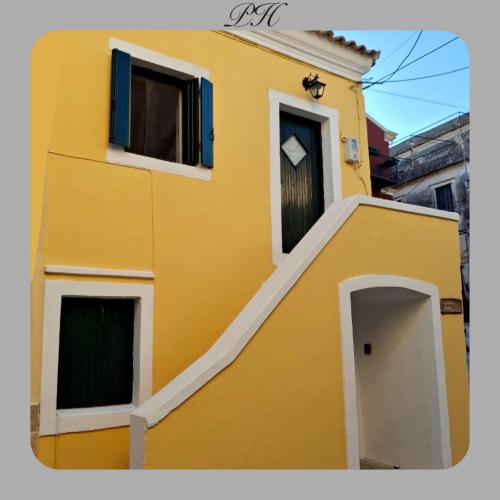 a yellow building with two windows and a doorway at Pozzo House Corfu - Traditional House for 3 near Agios Georgios Beach in Argyrádes