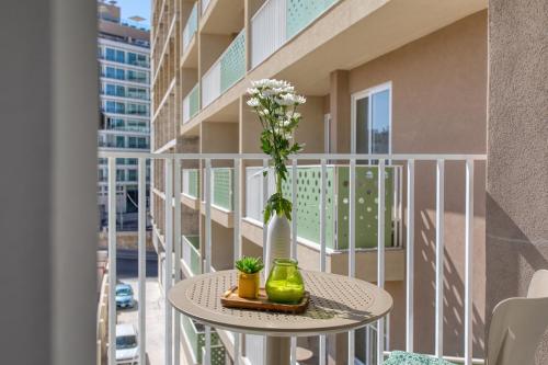 a table with a vase and flowers on a balcony at Stylish Apartment Heart of St Julians Sleeps 5 in San Pawl il Bahar