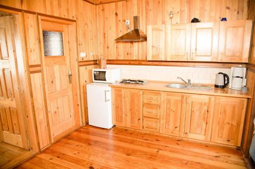 a kitchen with wooden cabinets and a white refrigerator at Domki Letniskowe Bursztynek in Grzybowo