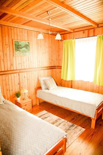 a room with two beds in a wooden cabin at Domki Letniskowe Bursztynek in Grzybowo