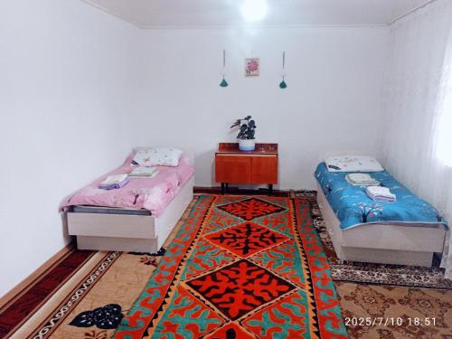 two beds in a room with a rug at NUR House in Kara-Koo