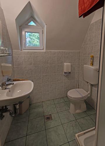 a bathroom with a sink and a toilet and a window at Garden Szálláshely in Balatonszemes