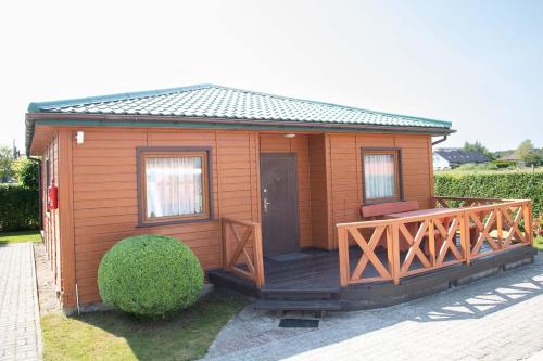 a small wooden cabin with a wooden deck at Domki Letniskowe Bursztynek in Grzybowo