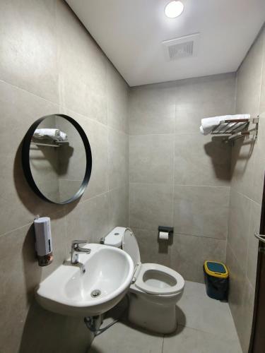 a bathroom with a sink and a toilet and a mirror at Pollux Habibie Batam Polux in Batam Center