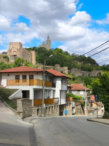 a house on a hill with a castle in the background at Tarnovka - Guest Rooms in Veliko Tŭrnovo