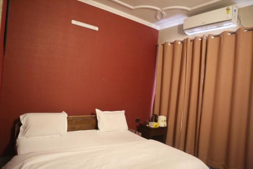 a bedroom with a bed and a red wall at Vedic Dham Ganga in Rishīkesh