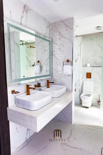 a bathroom with two sinks and a mirror and a toilet at The Mavvel Hotel in Kangaru