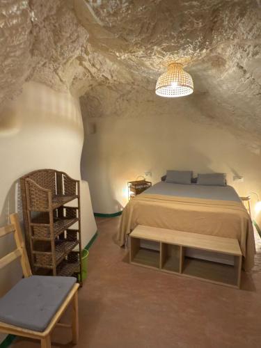 a bedroom in a cave with a bed and a chair at Bellísima cueva acogedora "Casa Olivia" in Gor