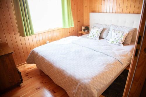 a bedroom with a large white bed with a window at Domki Letniskowe Bursztynek in Grzybowo
