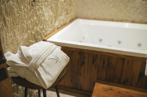a pile of towels sitting on a stool next to a bath tub at Vie Cappadocia - Adults Only in Nevsehir
